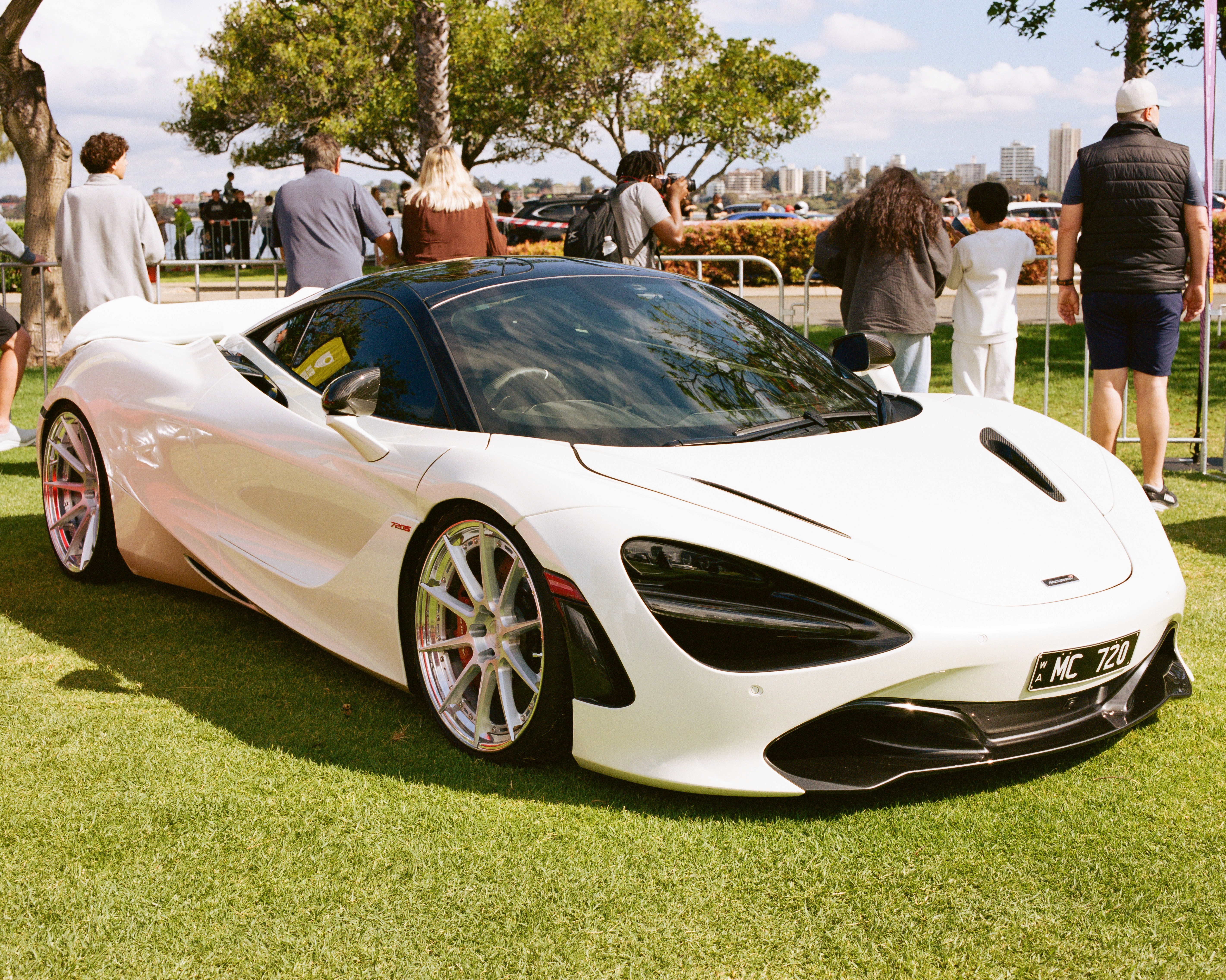 White McLaren 720S on grass at a car meet.